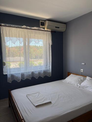 a bed in a room with a window with white sheets at Kiki's Place in Nikiti