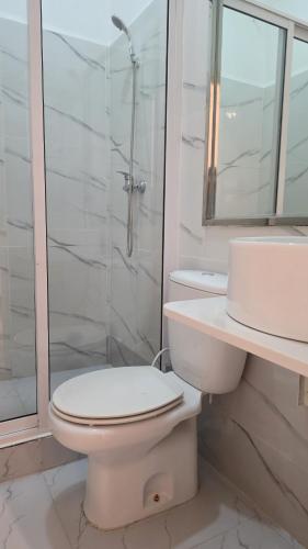 a white bathroom with a toilet and a shower at Pérola Suítes Boutique Hotel in Luanda
