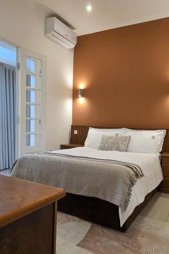 a bedroom with a large bed with a brown wall at Pérola Suítes Boutique Hotel in Luanda