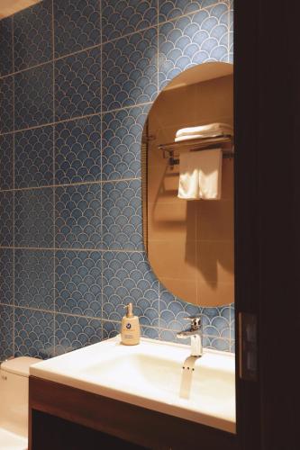 a blue tiled bathroom with a sink and a mirror at Sonasea Van Don Letavia Hotel in Thâm Câu