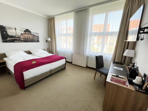 a hotel room with a bed and a desk and windows at Hotel Vita Berlin-Messe in Berlin