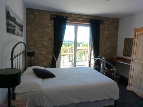 a bedroom with a bed and a large window at La Grange des Lavandes in Mérinchal