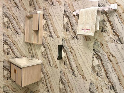 a bathroom with a marble wall with a sink and a towel at Appart Hotel Les orchidees in Cotonou