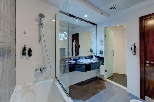 a bathroom with a glass shower and a sink at Ramada Abu Dhabi Corniche in Abu Dhabi