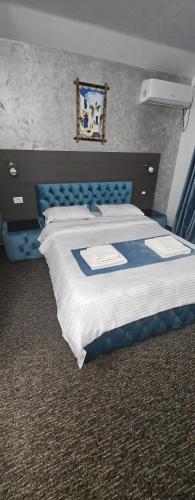 a large bed in a room with a blue headboard at Danube Home in Ostrovu Corbului