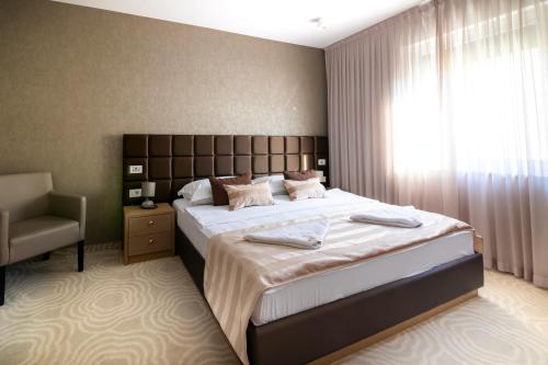 a bedroom with a large bed and a chair at Royal Airport Hotel in Velika Gorica