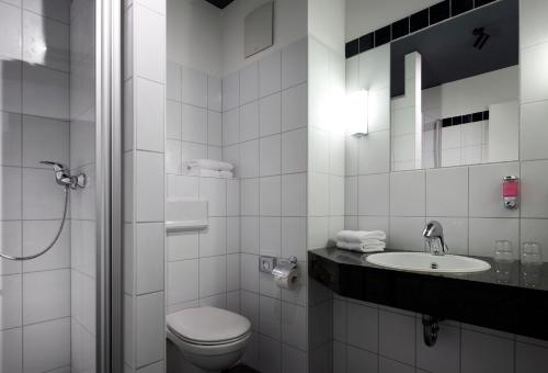 ein weißes Bad mit einem WC und einem Waschbecken in der Unterkunft Dom Hotel in Osnabrück