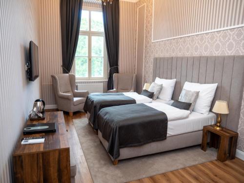 a bedroom with a bed and a chair and a window at Hotel Kaštieľ Mojmírovce in Mojmírovce