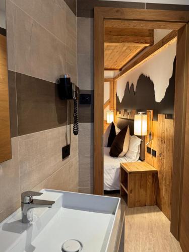 a bathroom with a sink and a bedroom with a bed at Lady Maria Hotel Wellness & Resort in Fondo