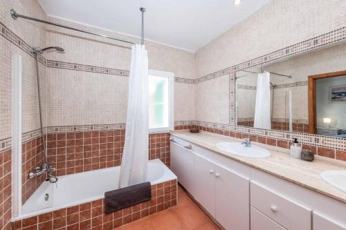 a bathroom with two sinks and a tub and a shower at Villa Olga in Cala en Porter