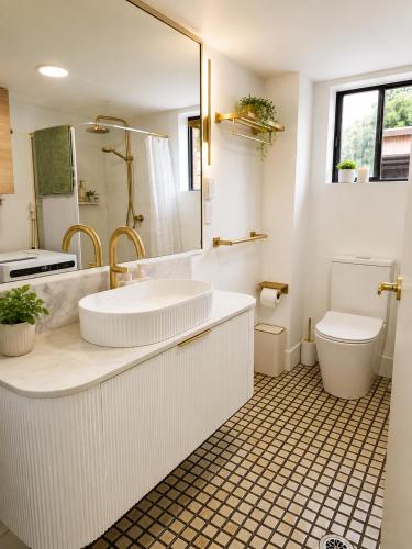 a white bathroom with a sink and a toilet at Dunes Apartment Unit 8- GROUND FLOOR WITH POOL VIEW in Coffs Harbour