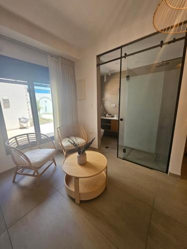 a living room with a glass shower and a table and chairs at קציר ריזורט in Migdal