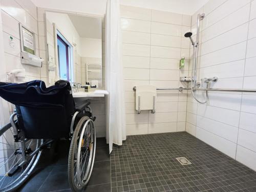 a wheelchair sitting in a bathroom with a shower at Hotel Vita Berlin-Messe in Berlin