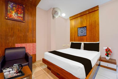 a bedroom with a bed and a chair at Townhouse Oak Kozhikode Bus Stand Formerly Nextel Inn in Kozhikode