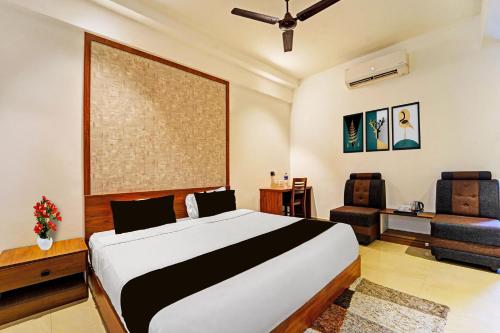 a bedroom with a large bed and a chair at Townhouse Kozhencherry Formerly The Beige Hotel in Pathanāmthitta