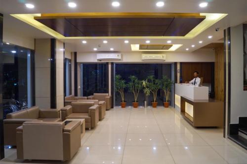 a lobby of a hotel with a man standing at a counter at Hotel Midtown in Vadodara