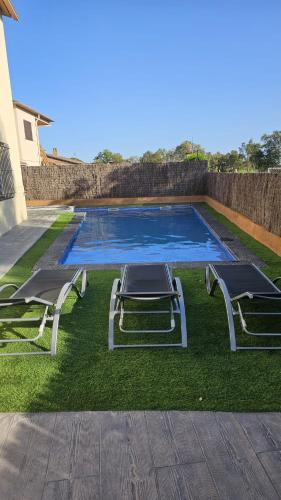 two chairs and a swimming pool in the grass at Villadora Piscina privada & jacuzzi Cerca de la costa brava in Santa Coloma de Farners