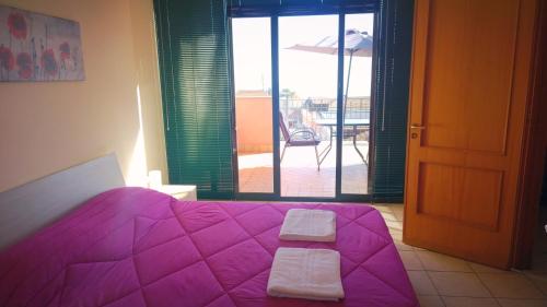 ザッフェラーナ・エトネーアにあるZafferana Apartmentの紫色のベッドとバルコニー付きのベッドルーム1室