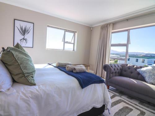 a bedroom with a bed and a couch and a window at Bluemist Accommodation in Gansbaai