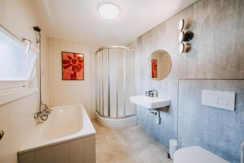 a bathroom with a sink and a tub and a toilet at Villa Limoncello in Hard
