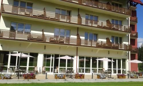 a hotel with tables and umbrellas in front of it at Hotel TTS**** Spa&Wellness Covasna in Covasna