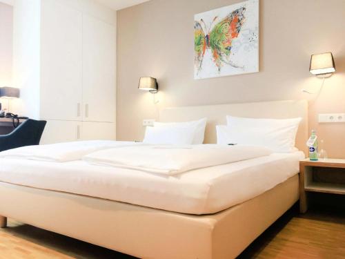 a large white bed in a bedroom with two lights at zeitwohnhaus SUITE-HOTEL & SERVICED APARTMENTS in Erlangen