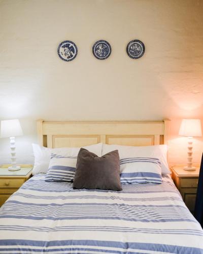 a bed with two blue and white plates on the wall at Beach Cottage Abigail in Southbroom