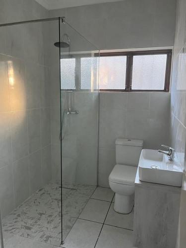 a bathroom with a shower and a toilet and a sink at Beach Cottage Abigail in Southbroom
