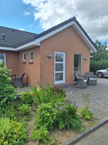 a brick house with a patio with chairs and flowers at Nice room with a wonderful view in Sommersted