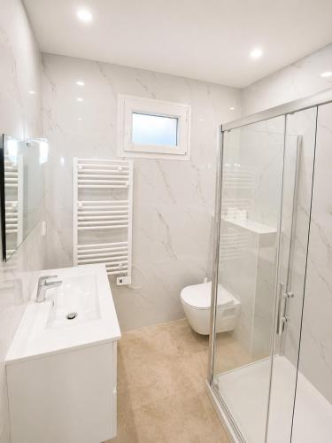a white bathroom with a sink and a shower at Maison moderne Parking &Jardin in Narbonne