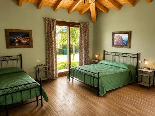 a bedroom with two green beds and a window at Podere Meroli in Scorcetoli