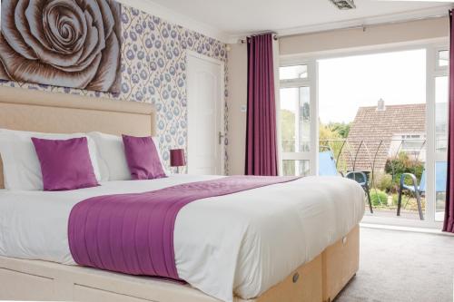 a bedroom with a large bed with purple pillows at Talbot House by Grandeur Property in Bournemouth