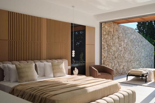a bedroom with a large bed and a chair at Doci Kelios - Serenity Suites with Private Heated Pools, by ZanteWize in Agios Nikolaos