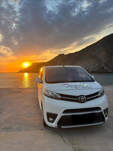 a white car parked on the beach with the sunset at The Anafians Studios in Anafi