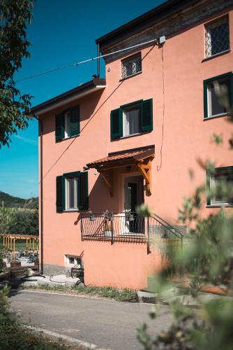 a pink building with green shutters and a balcony at Casa Praie in Casasco