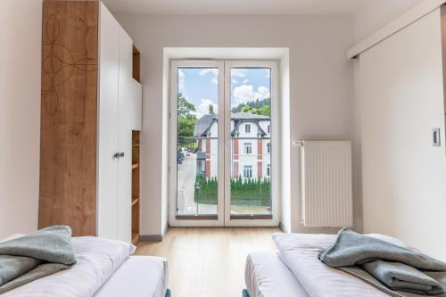 a living room with two beds and a large window at APARTAMENTY ZDROJOWA 9 in Duszniki Zdrój