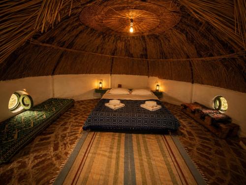 a room with a bed in a thatched room at La Colibe, cătun arhaic ecologic in Corbu