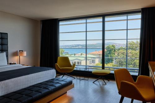 a hotel room with a bed and chairs and a large window at Metropolitan Hotels Bosphorus - Special Category in Istanbul
