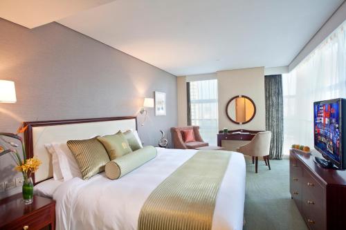 una camera d'albergo con un grande letto e una TV di Regal Plaza Hotel & Residence a Shanghai
