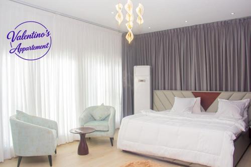 a bedroom with a bed and a chair at Valentinos Appartement Prestige in Agbodrafo