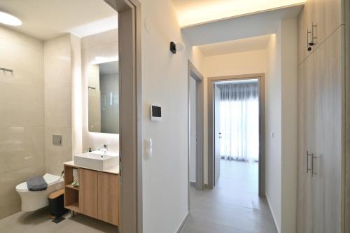 a bathroom with a sink and a toilet and a mirror at Apex Premium Living in Leptokarya