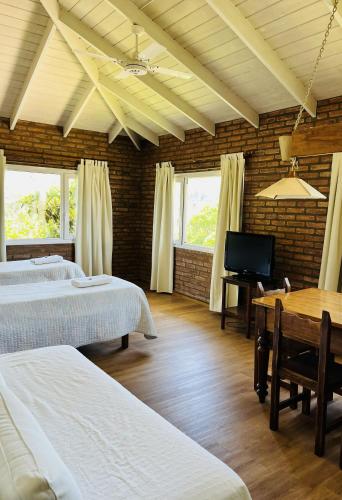 a room with two beds and a television and a table at Hostería La Viña in La Cumbre