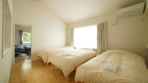 two beds in a room with a window at maison de plum in Nasushiobara