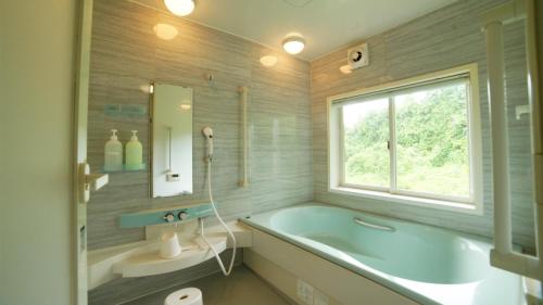 a bathroom with a blue tub and a window at maison de plum in Nasushiobara
