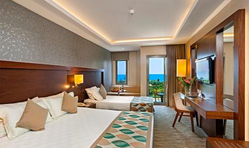 a hotel room with two beds and a desk at Belconti Resort Hotel in Belek