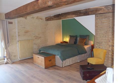 a bedroom with a bed and a chair at Ferme La Hougue B&B in Coigny