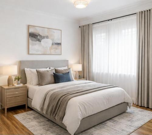 a white bedroom with a large bed and a window at Barnard Beach House in Broadwater