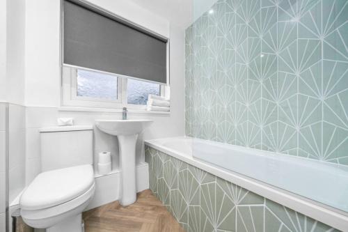 a bathroom with a tub and a toilet and a sink at 3-Bed Home in East Kilbride Ideal for Contractors & Longer Stays from Voyage Collection in East Kilbride