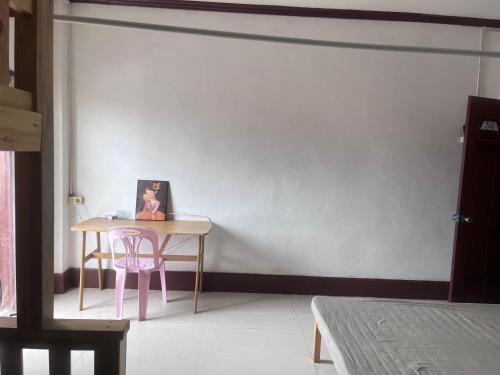 a table in a room with a pink chair and a picture at FUBON World Guesthouse in Ban Nongpapao