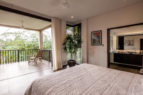 a bedroom with a bed and a balcony at Villa Naga Putih in Ubud